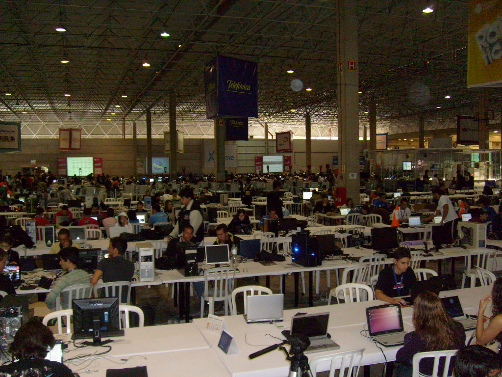 Foto das mesas com e pessoal sentado usando os computadores