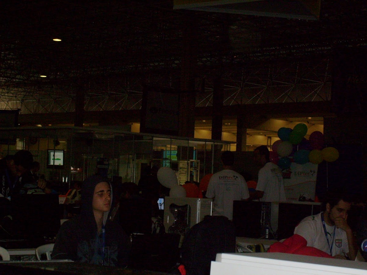 Foto escura de algumas pessoas mexendo no computador
