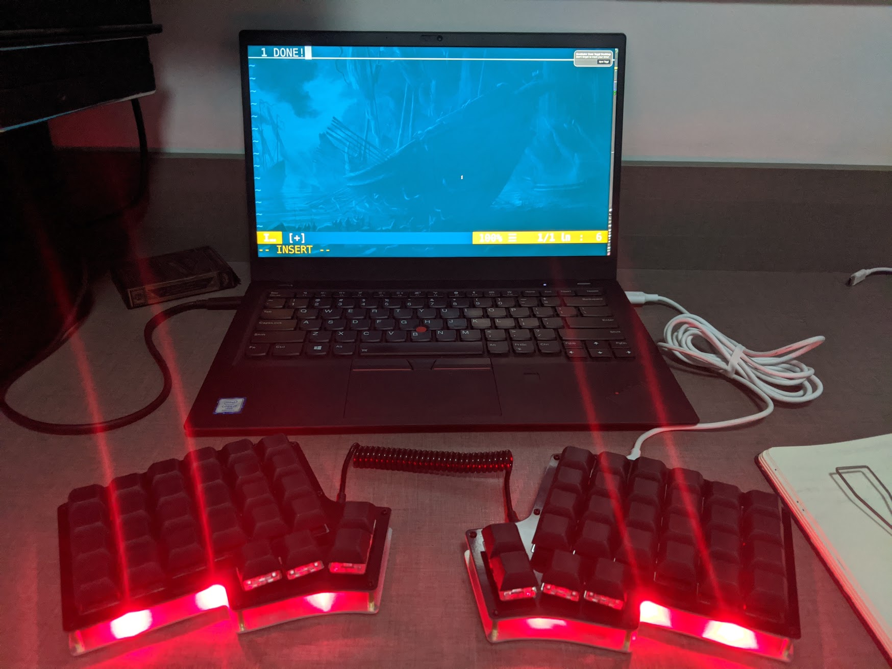 The laptop running Vim with the text &ldquo;DONE!&rdquo; written. The completed keyboard with red LEDs below